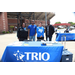 A group of individuals standing behind a table that reads &quot;TRIO&quot;