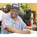 A man in a hat smiling and eating watermelon