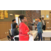 three adults sitting at table and lady standing nearby