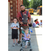 Man with beard and glasses, wearing baby pack, pushing stroller and with a little boy