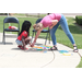 A woman helping a young girl play with toys on a sidewalk