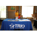 A woman and two children at a table that reads &quot;TRIO Educational Opportunity Center&quot;