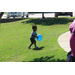 A boy walking through grass with a balloon