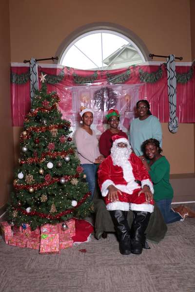 4 people posing behind seated Santa and Christmas tree