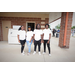 A group of four all pose together in matching shirts. 