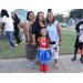 Three women posing with a young girl in a Wonder Woman costume. 