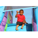 A young boy sitting on the bounce slide holding up a treat in a cup with a spoon. 