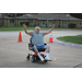 A gentleman in a motorized wheelchair smiling with his hands in the air. 
